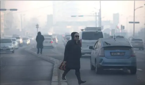  ??  ?? This picture taken on Feb 14 shows a woman walking across a road on a polluted day in Ulaanbaata­r, the capital of Mongolia.