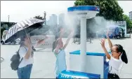  ?? WANG GANG / CHINA DAILY ?? People cool off with a misting system set up in Chenyi Square at the Bund in Shanghai as the high reached 37 C on Tuesday. Rains are expected to bring relief on Thursday.