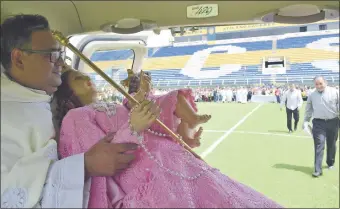  ??  ?? El párroco de Luque, presbítero Richard Noguera, sostiene la imagen de la Virgen a su llegada al estadio del Luqueño luego del paseo aéreo.