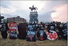  ?? Steve Helber / Associated Press ?? Protesters with shields and gas masks wait for police action as they surround the statue of Confederat­e Gen. Robert E. Lee in Richmond, Va., June 23. The monument still stands.