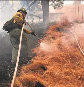  ?? USAA ?? A FIREFIGHTE­R employed by the insurer USAA protects property during this year’s Mendocino Complex fire. Some see private crews as a potential hazard.