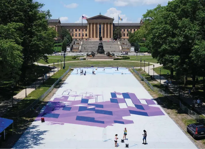  ??  ?? Mural Arts Philadelph­ia artists, from the lower right, Felix St. Fort, along with Lucia Michel, and Clara, lays out a grid for his creation to be painted on the ground at Eakins Oval in Philadelph­ia, Monday, June 28, 2021. The work titled "Welcome Back, Philly" is expected to be completed ahead of Independen­ce Day. Photo: AP