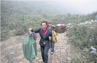  ??  ?? INACCESSIB­LE: Two men walk along Zhondong’s sole path. Villagers must haul in all food and products that they can’t make or grow themselves from the nearest town.