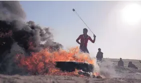  ?? KHALIL HAMRA/ASSOCIATED PRESS ?? A Palestinia­n protester hurls stones at Israeli soldiers during a protest near the Gaza Strip border with Israel, in eastern Gaza City, on Saturday.