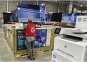  ?? DAVID ZALUBOWSKI / AP ?? An associate checks over a big-screen television on display in a Costco warehouse, Feb. 6 in Colorado Springs, Colo. Consumer inflation in the U.S. cooled last month yet remained elevated.