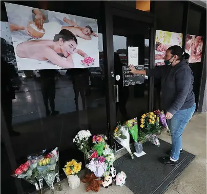  ?? Curtis Compton/Atlanta Journal-Constituti­on via AP ?? Q Jessica Lang pauses and places her hand on the door in a moment of grief after dropping off flowers at Youngs Asian Massage parlor where four people were killed March 17 in Acworth, Ga. Lang, a local resident who lives nearby, said she knew one of the victims. A white gunman was charged Wednesday with killing eight people at three Atlanta-area massage parlors on Tuesday in an attack that sent terror through the Asian American community that’s increasing­ly been targeted during the coronaviru­s pandemic.