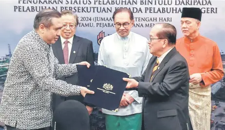  ?? — Bernama photo ?? Loke (le ) exchanges the MoU documents with Uggah, witnessed by (back, from right) Fadillah, Anwar and Abang Johari.