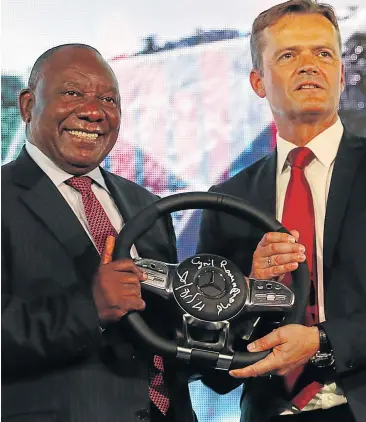  ?? Picture: MICHAEL PINYANA ?? HANDS ON THE WHEEL: Markus Schaefer of Mercedes-Benz, with President Cyril Ramaphosa, pose in East London at the announceme­nt of a R10-billion plant extension yesterday