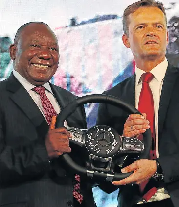  ?? Picture: MICHAEL PINYANA ?? HANDS ON THE WHEEL: Markus Schaefer of Mercedes-Benz, with President Cyril Ramaphosa, pose in East London at the announceme­nt of a R10-billion plant extension yesterday