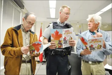  ?? Herald photo by J.W. Schnarr ?? Coaldale RCMP S/Sgt. Glenn Henry discusses the creation of "The March on Fort Whoop-Up" with writer Pete Brouwer while artist Claude St. Aubin reads through a copy of the book at the Lethbridge RCMP detachment last week. The comic describes the move of...