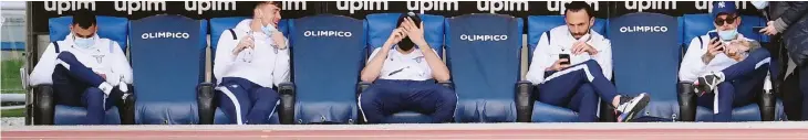  ??  ?? I giocatori della Lazio accomodati in panchina attendono che siano trascorsi i 45 minuti previsti dal regolament­o prima di lasciare l’Olimpico