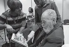  ??  ?? Lanita Prentis, left, a former debate team member, shows Freeman an old photograph of the 1980-81 team Saturday.