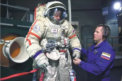  ?? NATALIA KOLESNIKOV­A / AGENCE FRANCE-PRESSE ?? Russian cosmonaut Sergei Ryazansky tries on his galaxian garb for size at Star City space-training center near Moscow in May.