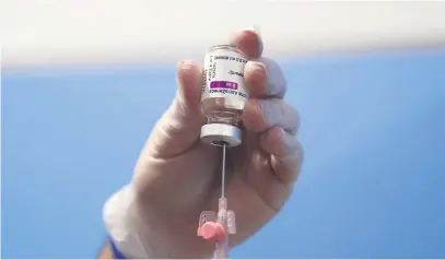  ??  ?? A health worker prepares a dose of the AstraZenec­a vaccine