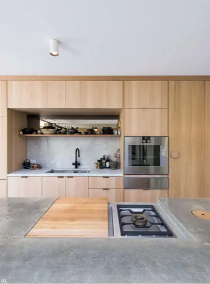  ??  ?? 03 02 A void above the living areas lets plenty of light in, which is perfect for the owners, who spend a lot of time entertaini­ng in the kitchen. Artwork: Michael Muir.
03 The custom off-form concrete island bench features bespoke elements, including a timber chopping board that covers the cooktop.