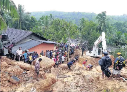  ?? Eranga Jayawarden­a ?? > Sri Lankans watch military rescue efforts at the site of a landslide at Bellana village