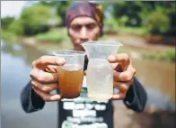  ?? DARREN WHITESIDE / REUTERS ?? An Indonesian man compares cups of water from the Citarum river (left) and from a tributary where the two meet near the city of Bandung.