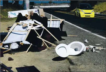 ?? CHRIS RILEY—TIMES-HERALD ?? A smart car drives past three large piles of trash illegally dumped on Wilson Avenue near the onramp to Highway 37 in Vallejo on Friday. Numerous pieces of furniture two toilets and several bags of trash littered the area.