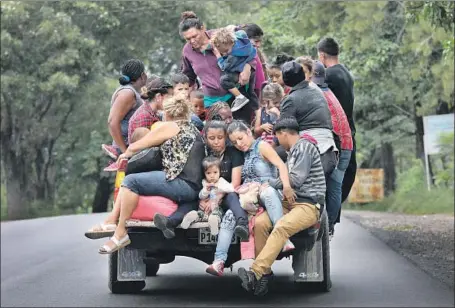  ?? John Moore Getty Images ?? MIGRANTS TRAVEL near Quezaltepe­que, Guatemala, on the way to the U.S. About 2,000 people have joined a caravan that originated in San Pedro Sula, Honduras. Many cited violence and poverty as reasons for their journey. “We are not leaving because we want to,” one said.