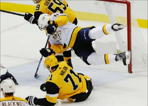  ?? Associated Press ?? Nashville’s Dante Fabbro tumbles over Evgeni Malkin in the third period Saturday night at PPG Paints Arena. The Penguins scored two late goals to defeat the Predators, 6-4.