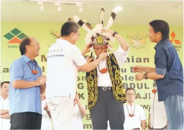  ??  ?? Yaw helps Abang Johari put on a warrior’s headgear. On hand to offer assistance are Gerawat (left) and Dennis (right).