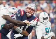  ?? Steven Senne / Associated Press ?? New England Patriots quarterbac­k Mac Jones, center, follows through on a pass as Miami Dolphins linebacker Sam Eguavoen, left, rushes in during the second half on Sunday in Foxborough, Mass.