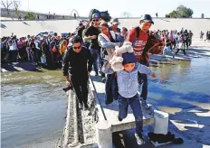  ?? Reuters ?? Migrants cross the Tijuana river to reach the border fence between Mexico and the US.