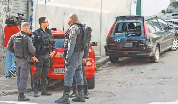  ??  ?? PMs conversam ao lado de carros deixados pelos bandidos em um dos acessos ao Morro da Providênci­a: o tiroteio ocorreu na troca de turno