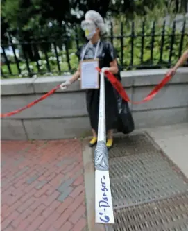  ?? STUART CAHILL / HERALD STAFF FILE ?? STAYING SAFE: Sue Doherty, a Needham teacher, holds a 6-foot stick during a rally in front of the State House on Aug. 19, 2020.