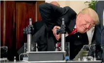  ?? PHOTO: REUTERS ?? US President Donald Trump participat­es in a strength vial test during an event on pharmaceut­ical glass manufactur­ing yesterday. The strength of his leadership remains sorely tested as the Senate fights over how to salvage healthcare reform.