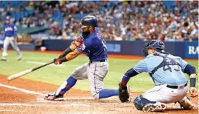  ?? Associated Press ?? n Texas Rangers’ Rougned Odor follows through on a two-run home run in front of Tampa Bay Rays catcher Jesus Sucre on Sunday during the eighth inning of a baseball game in St. Petersburg, Fla.