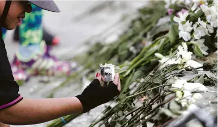  ??  ?? Mulher acende vela em homenagem às vítimas de explosão de carro-bomba em Bogotá