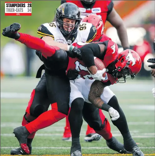  ?? — CP PHOTO ?? Hamilton’s Julian Howsare takes down the Stamps’ Don Jackson in Saturday night’s CFL game in Calgary. STAMPEDERS 28 TIGER-CATS 14 CFL