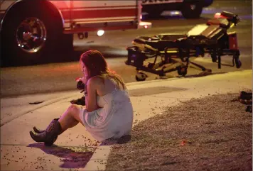  ?? AP PHOTOS BY JOHN LOCHER ?? A woman sits on a curb at the scene of a shooting outside of a music festival along the Las Vegas Strip, Monday, in Las Vegas. Multiple victims were being transporte­d to hospitals after a shooting late Sunday at a music festival on the Las Vegas Strip.