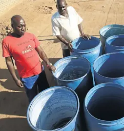  ?? / ANTONIO MUCHAVE ?? Community activist Steve Malatji, left, with empty water drums at the home of Matome Machipi whose son was scheduled to be buried on Saturday.