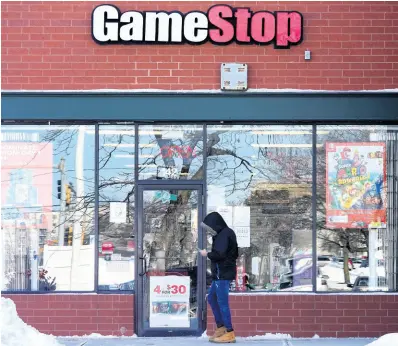  ?? AP ?? In this January 28 photo, a customer checks on his cell phone as he walks to a GameStop store.