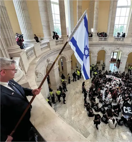  ?? ?? ► El representa­nte republican­o Brandon Williams ondea una bandera israelí sobre manifestan­tes en el Capitolio en Washington, 18 de octubre de 2023.