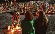  ?? Sean Gallup/Getty Images ?? Two women pause at a wreath while looking toward the graves of fallen Ukrainian soldiers on Friday.