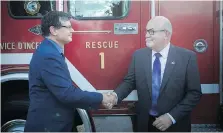  ??  ?? Lido Zuccato, left, chair of skilled trades at St. Clair College, thanks Tecumseh Mayor Gary McNamara for the donation of a 1990 model pumper truck.