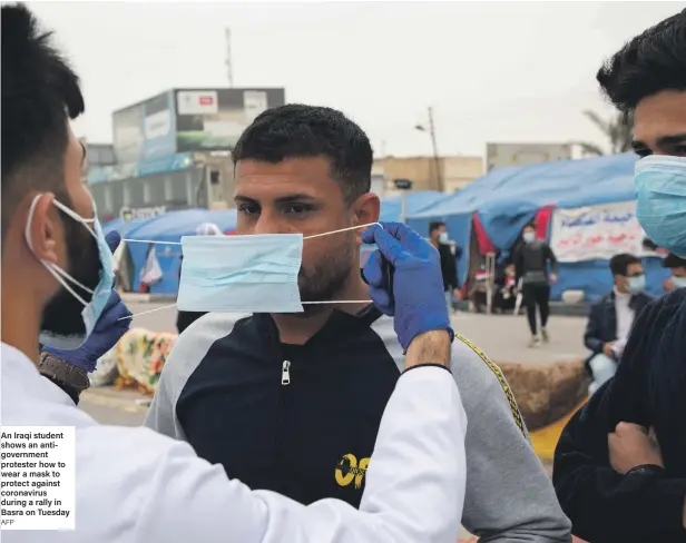  ?? AFP ?? An Iraqi student shows an antigovern­ment protester how to wear a mask to protect against coronaviru­s during a rally in Basra on Tuesday