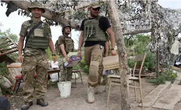  ??  ?? Ukrainian servicemen who fight against Russian-backed separatist­s carry boxes with pizza which had been delivered to the frontline.