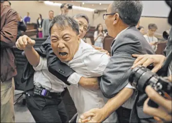  ?? Vincent Yu The Associated Press ?? Pro-democracy lawmaker Wu Chi-wai scuffles Saturday with security guards at the legislatur­e in Hong Kong. Lawmakers are in dispute over provisions to make it easier to send criminal suspects to mainland China.