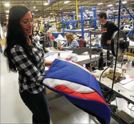  ?? PHOTOS BY PETE BANNAN — DIGITAL FIRST MEDIA ?? Deanna Erdman, marketing specialist, holds a custom designed seat cover at the USSC Group in Lionville, which manufactur­es custom seats for buses, firetrucks and the military.