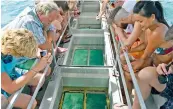  ?? — AFP ?? Tourists look at coral through a glass-bottomed boat on Australia’s Great Barrier Reef.