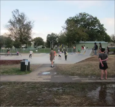  ?? DAN SOKIL — MEDIANEWS GROUP ?? Skaters wait on a paved path running through a muddy field adjacent to the skate area of the Lansdale skate park.