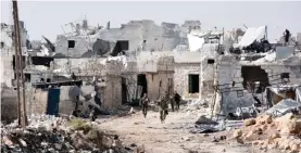  ??  ?? MINYAN, Syria: Syrian pro-government forces walk around in this village west of Aleppo after they retook the area from rebel fighters yesterday. — AFP