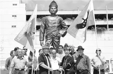  ??  ?? Bosi (right) submitting his membership form to Henrynus before the statue of Datuk Peter Mojuntin at Donggongon.