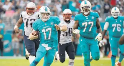  ?? JIM RASSOL/STAFF PHOTOGRAPH­ER ?? Dolphins QB Ryan Tannehill runs for a big first down to keep a drive alive late in Sunday’s season finals against the New England Patriots.