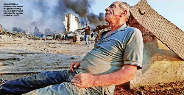  ?? AFP ?? DEVASTATED: A wounded man sits on the ground waiting for aid at Beirut’s port following the massive explosion. —