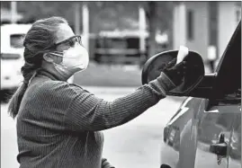  ??  ?? Mental health administra­tor Lynette Roach takes the temperatur­e of a man entering the Jack Mabley Developmen­tal Center in Dixon.